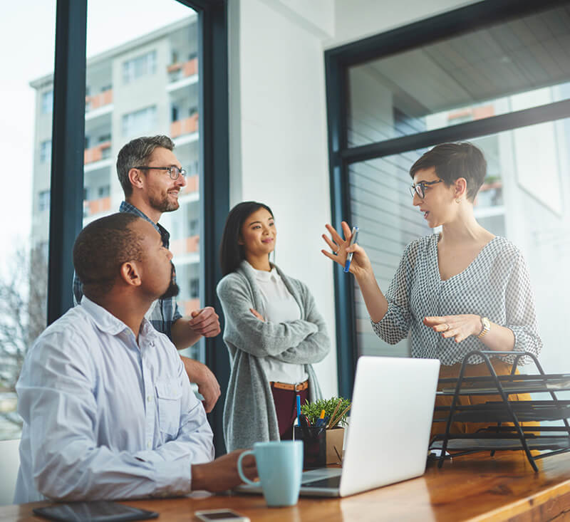 Female manager meeting with her team of three individuals in an office setting. 